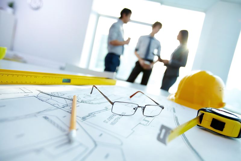 Project manager reviewing construction drawings with a hard hat on the desk